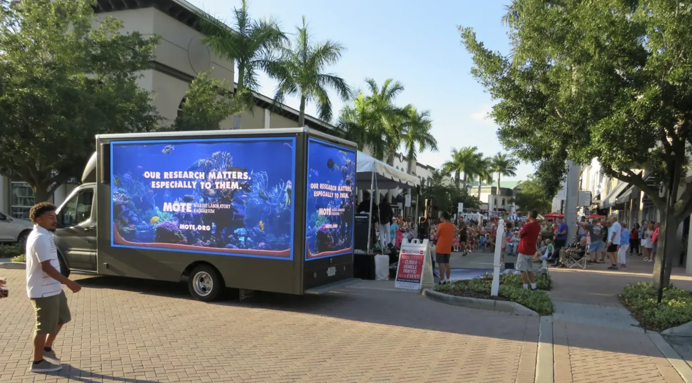 A Mote Marine Laboratory digital billboard truck playing underwater video at an outdoor festival